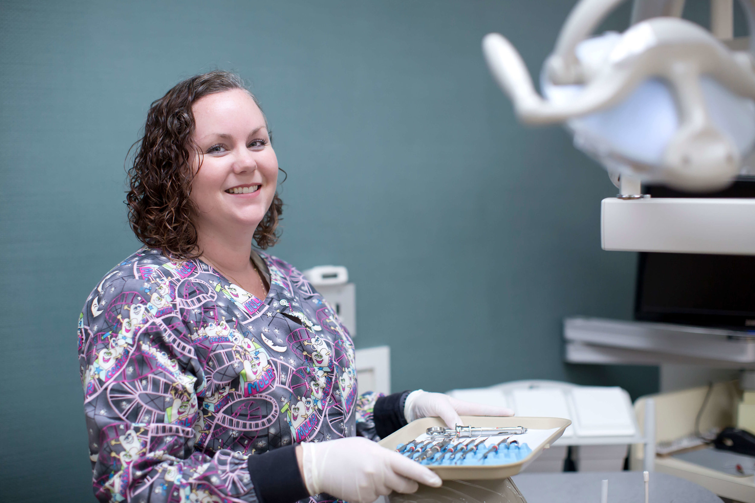A smiling dental professional holding a tray of instruments