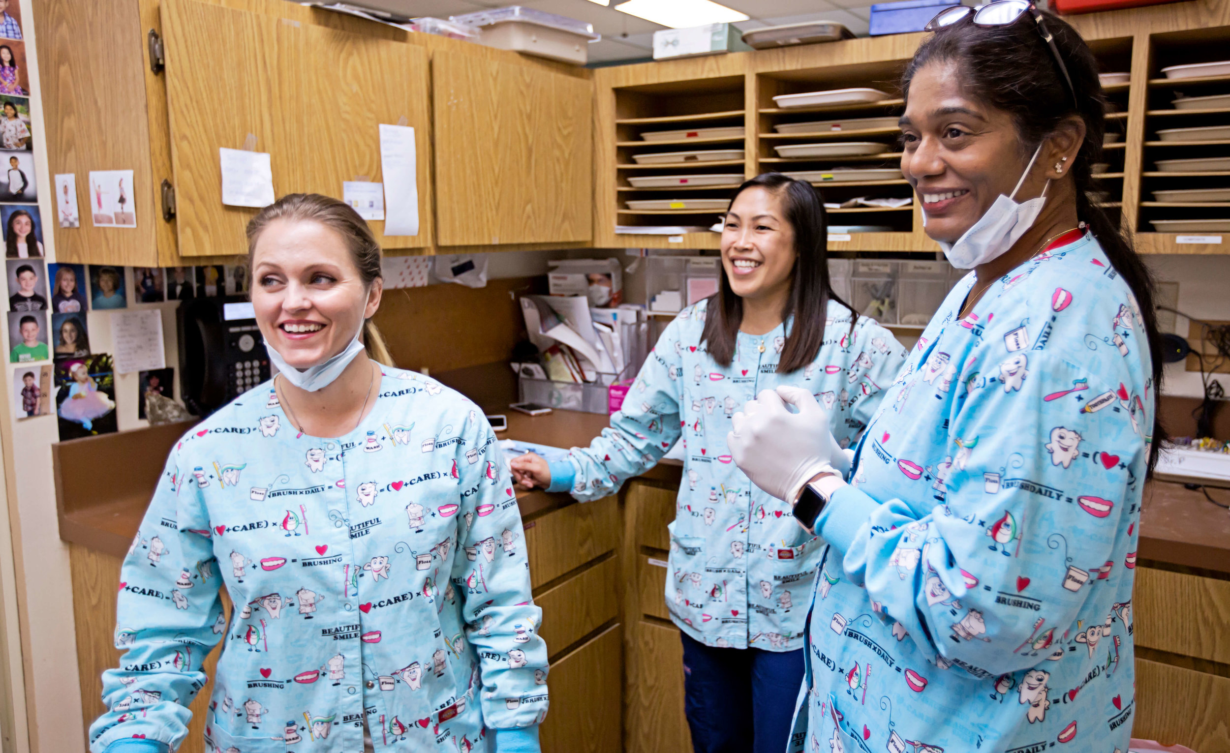 Three dental staff members smiling together in the office
